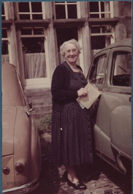 Photograph of Jean Milligan standing in front of a car
